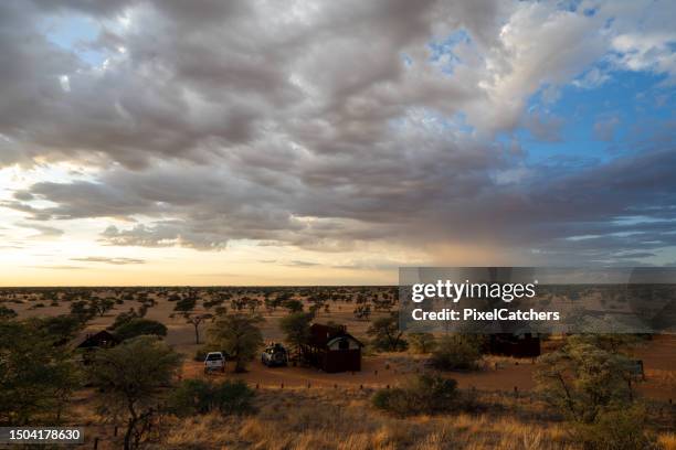 sunset over a tented camp in the kalahari desert with stormy clouds - kgalagadi transfrontier park stock pictures, royalty-free photos & images