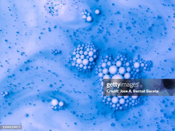 full frame of white liquid molecules floating on a blue liquid surface. - splash crown fotografías e imágenes de stock