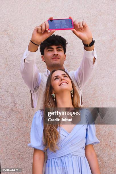 pretty girl and her boyfriend looking at their mobile phone while taking photos - girlfriend imagens e fotografias de stock