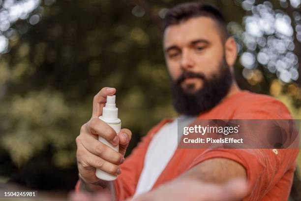 man applying insect repellent - fly spray stock pictures, royalty-free photos & images