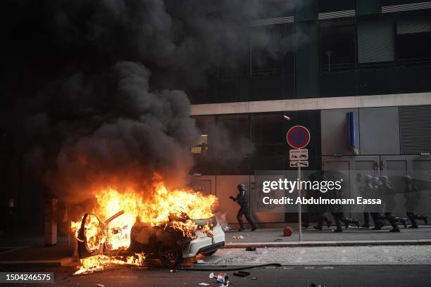 An overturned car burns during clashes between French police forces and youths after a memorial march for French teenager Nahel, shot by police...