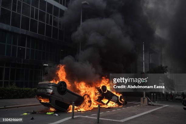 An overturned car burns during clashes between French police forces and youths after a memorial march for French teenager Nahel, shot by police...