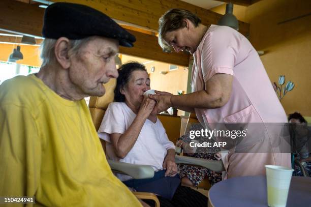Nursing home's employee helps an old person to drink on August 17 in Lormes, eastern France, during the visit of Social Affairs and Health Minister,...