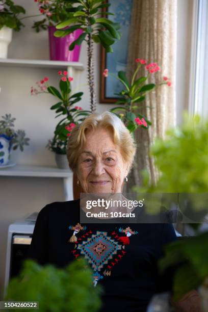 senior woman smelling flowers, on the balcony at home - 101cats stock pictures, royalty-free photos & images