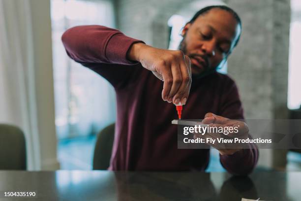 homme utilisant un kit d’autotest rapide pour détecter le covid-19 - kit pour tester photos et images de collection