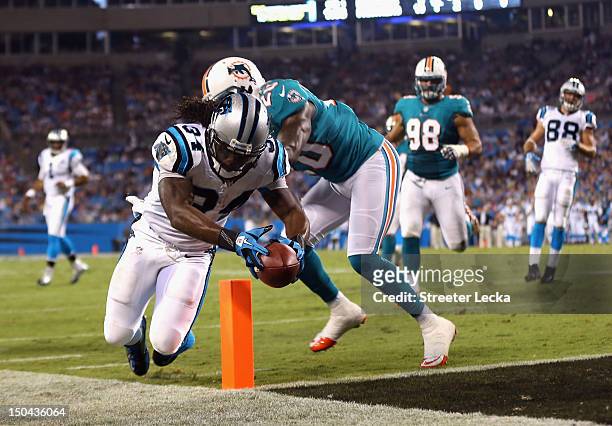 Reshad Jones of the Miami Dolphins tries to stop DeAngelo Williams of the Carolina Panthers as he dives for a touchdown during their preseason game...