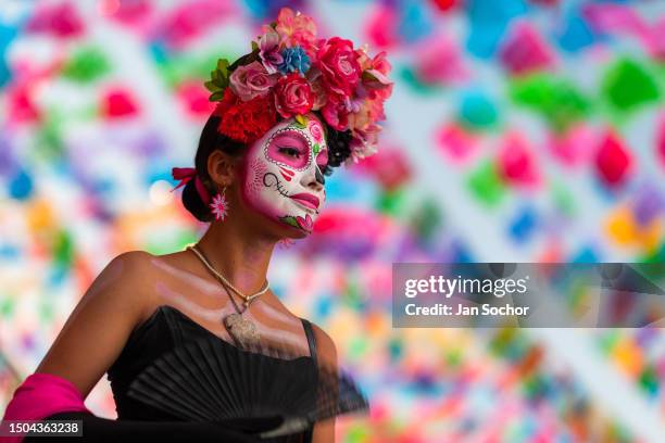 Young Mexican woman, dressed as La Catrina and fanning herself with a handfan, takes part in the Day of the Dead festivities on October 30, 2022 in...