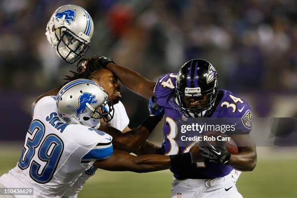 Jonte Green of the Detroit Lions looses his helmet while being stiff armed by Bobby Rainey of the Baltimore Ravens as Ricardo Silva pushes him out of...