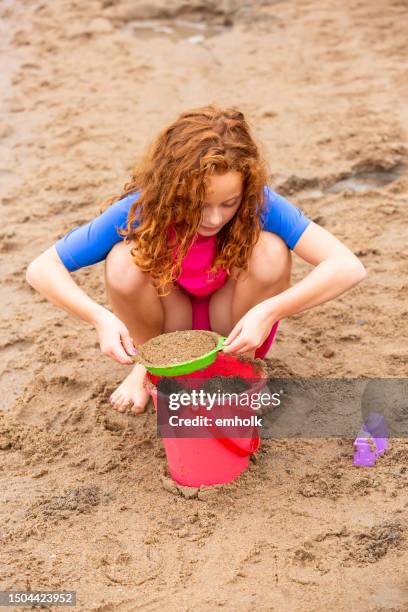 curly haired redhead girl at the beach - sifting stock pictures, royalty-free photos & images