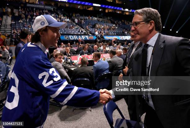 Hudson Malinoski shakes hands with team personnel after being selected 153rd overall by the Toronto Maple Leafs during the 2023 Upper Deck NHL Draft...