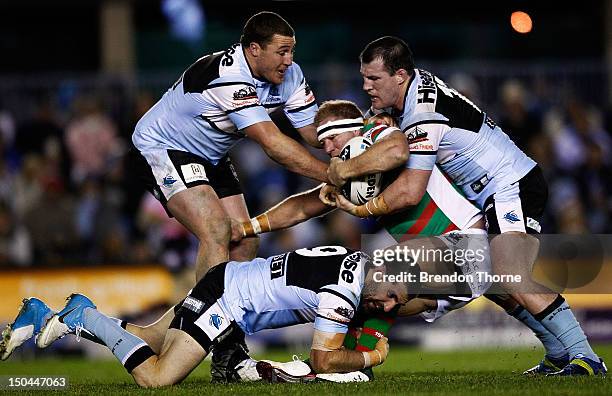 Michael Crocker of the Rabbitohs is tackled by the Sharks defence during the round 24 NRL match between the Cronulla Sharks and the South Sydney...