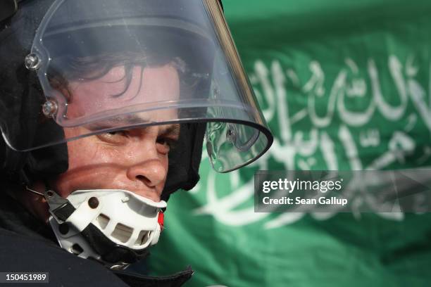 Policeman dressed in riot gear turns as a protester waves a flag with Arabic written on it demonstrators protest the arrival of supporters of the pro...