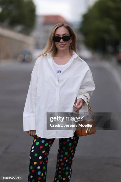 Sonia Lyson wearing Louis Vuitton brown logo mini leather bag with a gold strap, Loewe white logo tank top, white Storets oversized buttoned long...