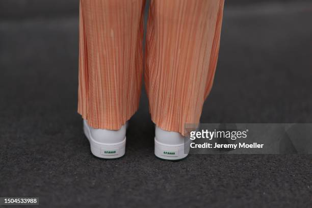 Sonia Lyson wearing Copenhagen Studios white and green sneaker, Storets orange pleated pants on June 28, 2023 in Berlin, Germany.