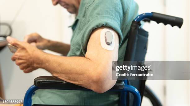 senior man using a continuous glucose monitor - diabetic amputation stock pictures, royalty-free photos & images