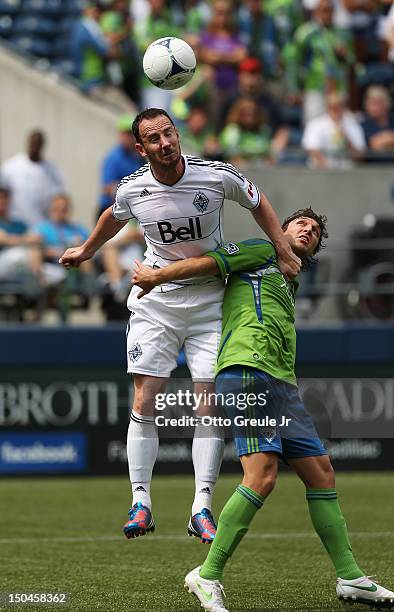 Andy O'Brien of the Vancouver Whitecaps heads the ball against Jeff Parke of the Seattle Sounders FC at CenturyLink Field on August 18, 2012 in...