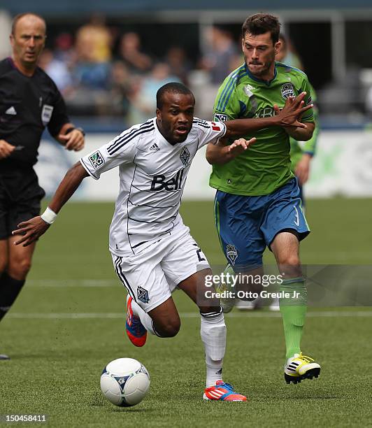 Dane Richards of the Vancouver Whitecaps dribbles against Brad Evans of the Seattle Sounders FC at CenturyLink Field on August 18, 2012 in Seattle,...