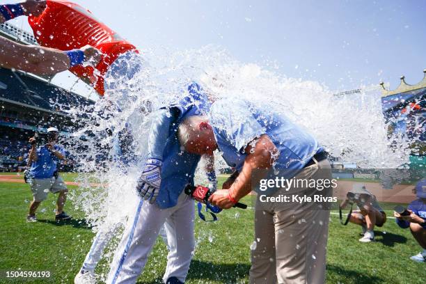 Joel Goldberg and Freddy Fermin of the Kansas City Royals are splashed with a bucket of water after Fermin hit a two run double to win the game...