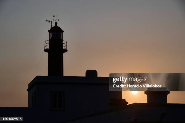 The sun setting over the sea is seen from Cabo Raso Lighthouse through a yellowish cloud of smoke provoked by huge forest fires affecting Canada,...