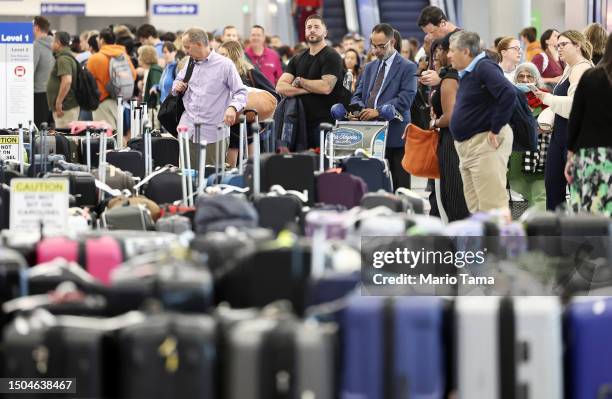 Travelers wait for their bags amid rows of unclaimed luggage at the United Airlines baggage claim area at Los Angeles International Airport on June...