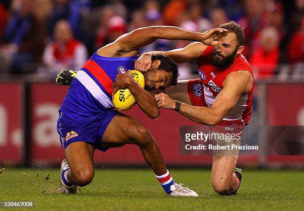 Nathan Djerrkura of the Bulldogs is tackled by Rhyce Shaw of the Swans during the round 21 AFL match between the Western Bulldogs and the Sydney...