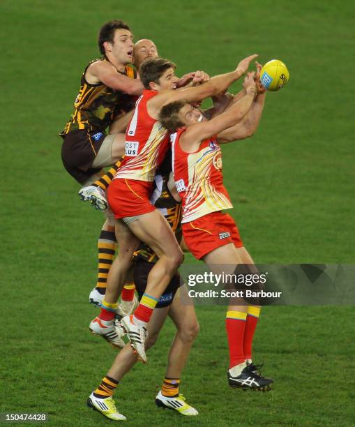 Jack Gunston of the Hawks along with Jeremy Taylor and Michael Coad of the Suns compete for the ball during the round 21 AFL match between the...