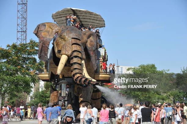 Metre high mechanical elephant, made of steel and wood, sprays water from its trunk over children and adults on August 19 at the site of Les Machines...