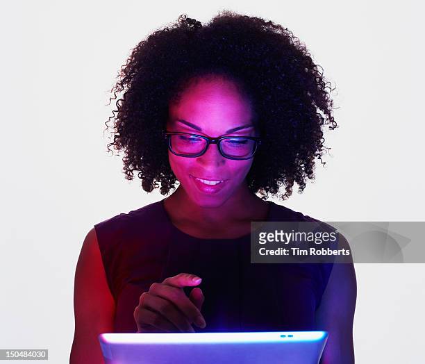 woman using and lit by a digital tablet. - holding digital tablet stock pictures, royalty-free photos & images