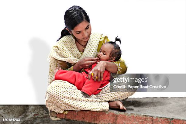 young mother feeding her baby sweet rice - nepal family stock pictures, royalty-free photos & images