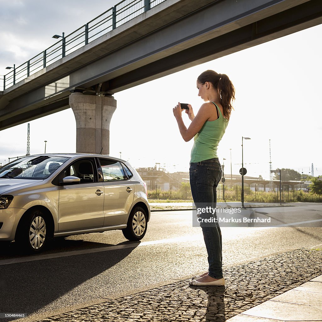 Woman taking picture of her car.