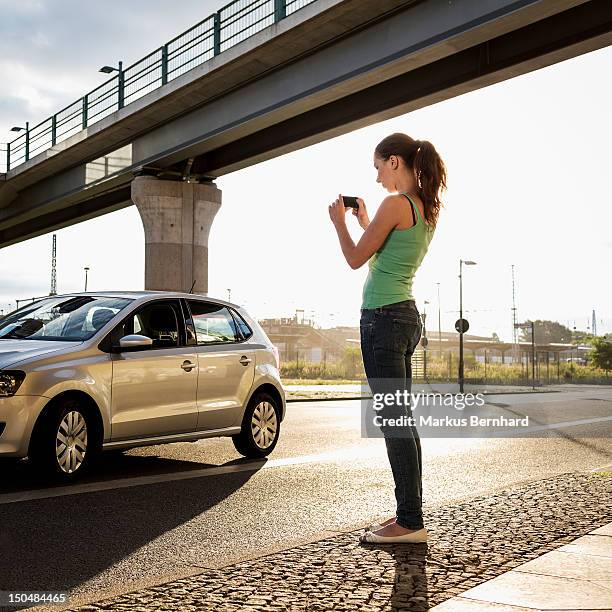 woman taking picture of her car. - car photo shoot stock pictures, royalty-free photos & images