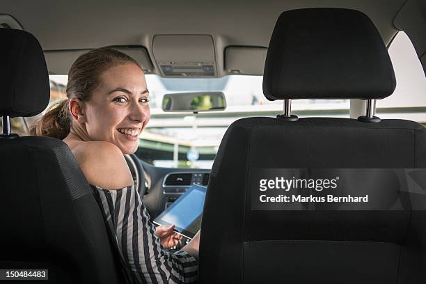 woman using tablet computer in her car. - drivers seat stock pictures, royalty-free photos & images