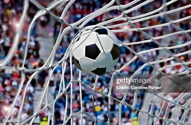 football, or soccer ball in the back of a net - scoring a goal stockfoto's en -beelden