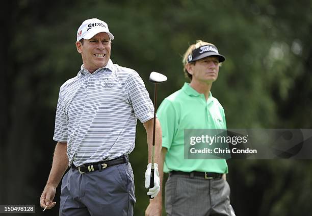 John Huston tees off on the second hole as Brad Faxon looks on during the final round of the Dick’s Sporting Goods Open at En-Joie Golf Course on...