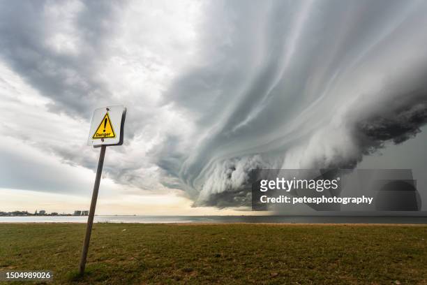 nube de tormenta masiva con lluvia debajo sobre el océano con una señal de peligro - ciclón fotografías e imágenes de stock