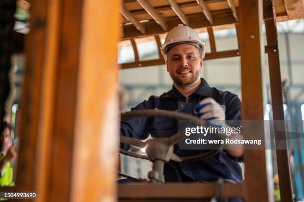 a forklift operator smiling while working - équipement de construction photos et images de collection