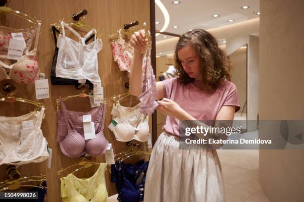 woman choosing lingerie in boutique - beha stockfoto's en -beelden