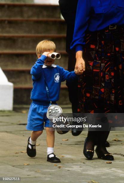 Prince Harry looks at photographers with a pair of binoculars as he leaves on his first day at Mrs. Mynor's nursery school on September 16, 1987 in...