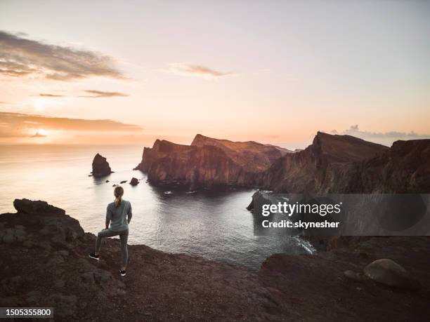 rear view of carefree woman on a cliff of ponta de sao lourenco at sunset. - europe train stock pictures, royalty-free photos & images