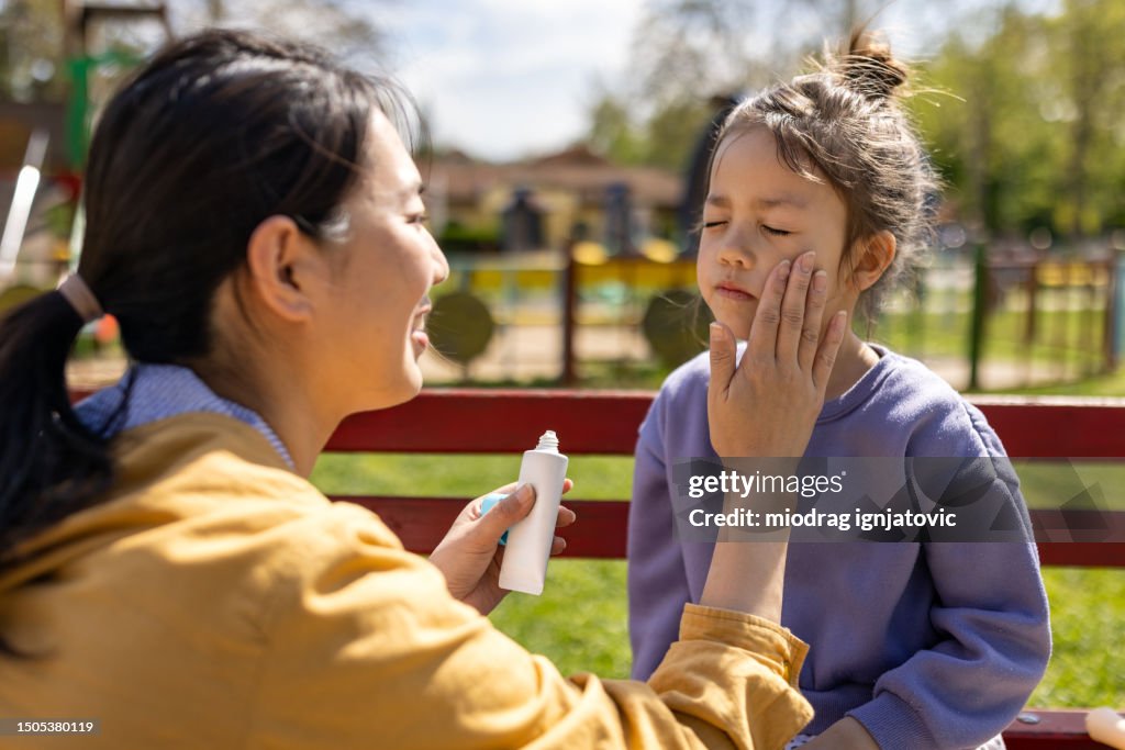 Mother applying sun-screen to her daughters face