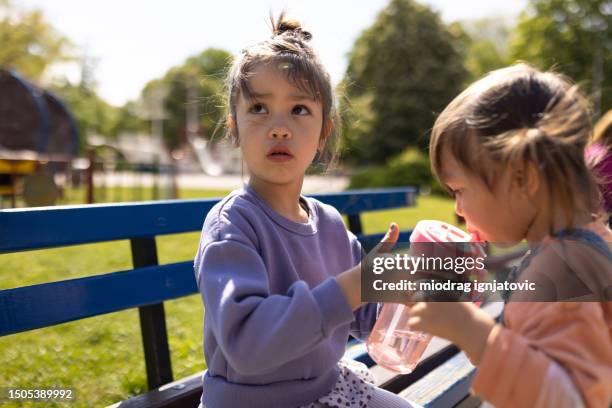 girls drinking water in a public park - thirsty stock pictures, royalty-free photos & images