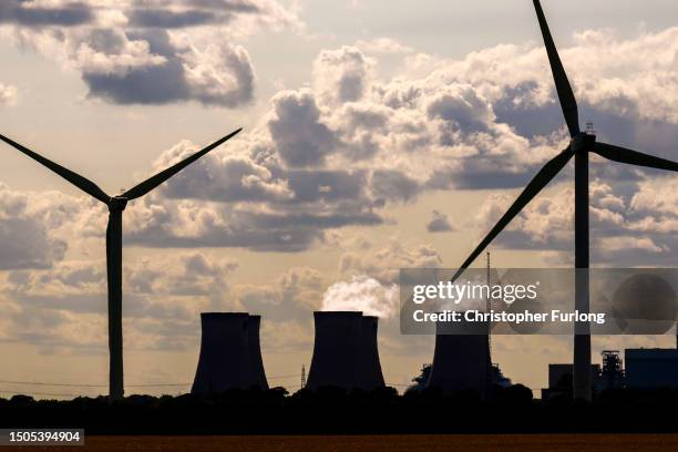 Wind turbines generate electricity as the Drax Power Station in the background also generates electricity on June 29, 2023 in Selby, England. The...