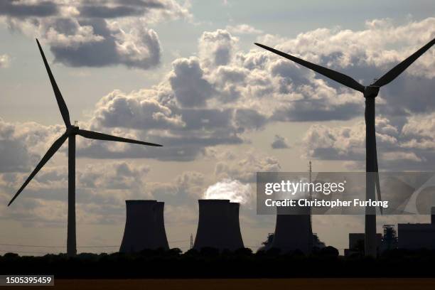 Wind turbines generate electricity as the Drax Power Station in the background also generates electricity on June 29, 2023 in Selby, England. The...