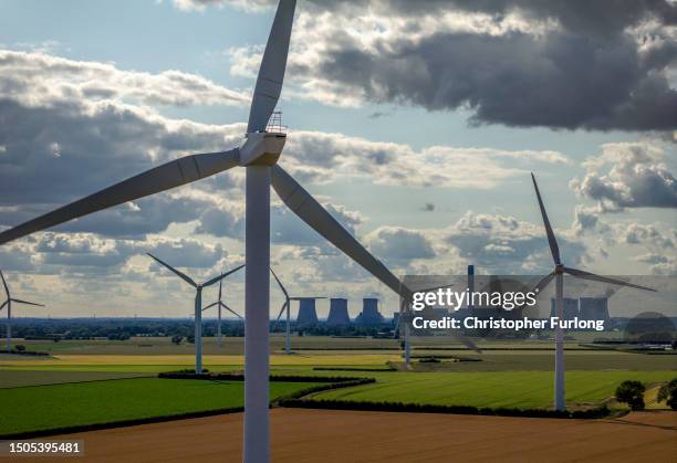 Wind turbines generate electricity as the Drax Power Station in the background also generates electricity on June 29, 2023 in Selby, England. The...