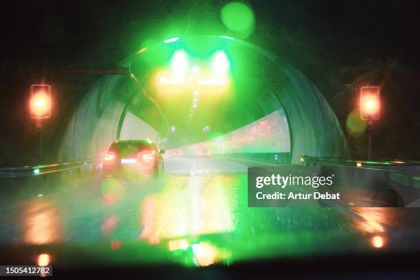 driving a car with caution at night under a torrential rain with water splashing. - car traffic light stock pictures, royalty-free photos & images