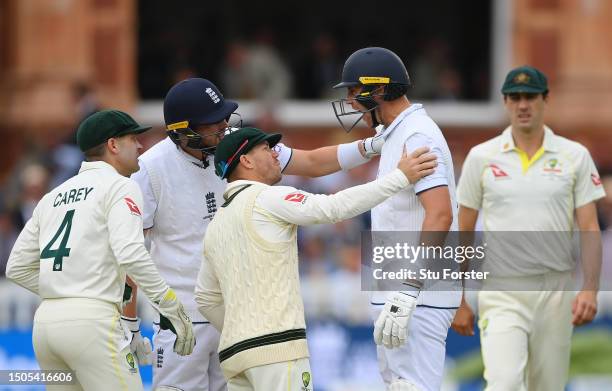 Stuart Broad of England is checked on by teammate Ollie Robinson and David Warner and Alex Carey of Australia after being stuck by the ball during...