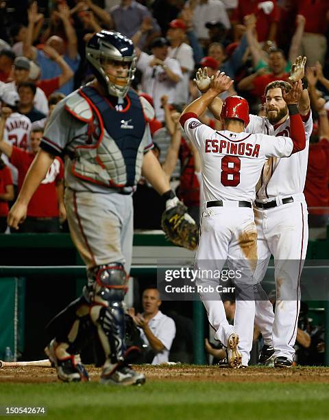 Danny Espinosa of the Washington Nationals celebrates scoring the winning run with teammate Jayson Werth as catcher Brian McCann of the Atlanta...