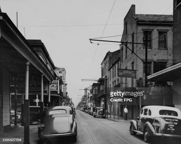 Cars parked along Bourbon Street, a sign for the 'Old Absinthe Bar' fixed to a building on the right of the street, in the French Quarter of New...