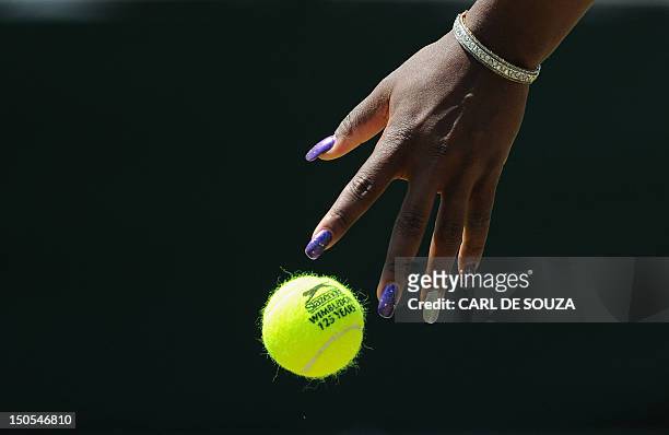 Player Serena Williams bounces the ball as she plays against Romania's Simona Halep in a Women's Singles match at the 2011 Wimbledon Tennis...