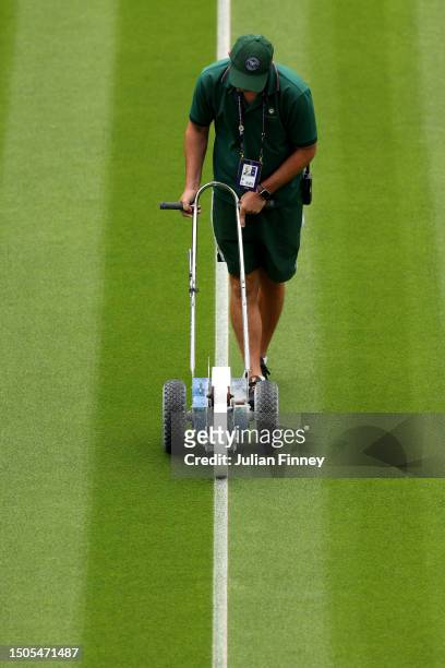 Member of ground staff paints the lines on the court ahead of The Championships - Wimbledon 2023 at All England Lawn Tennis and Croquet Club on June...